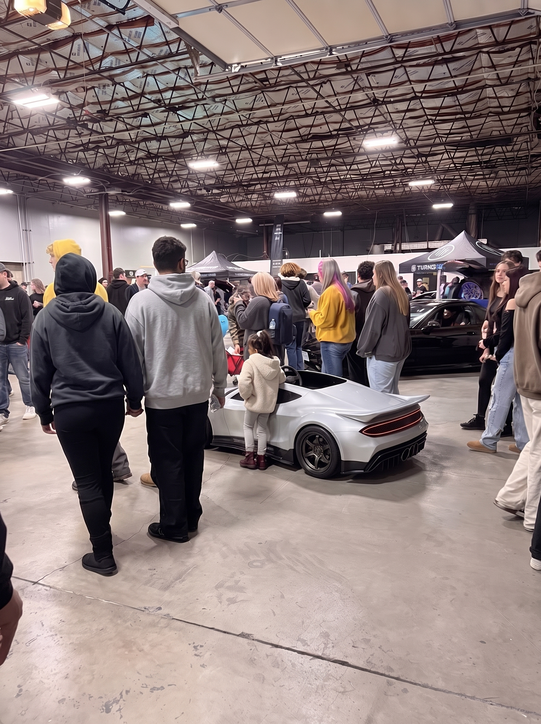 Crowd gathered around the GENOS R1 at an indoor car show